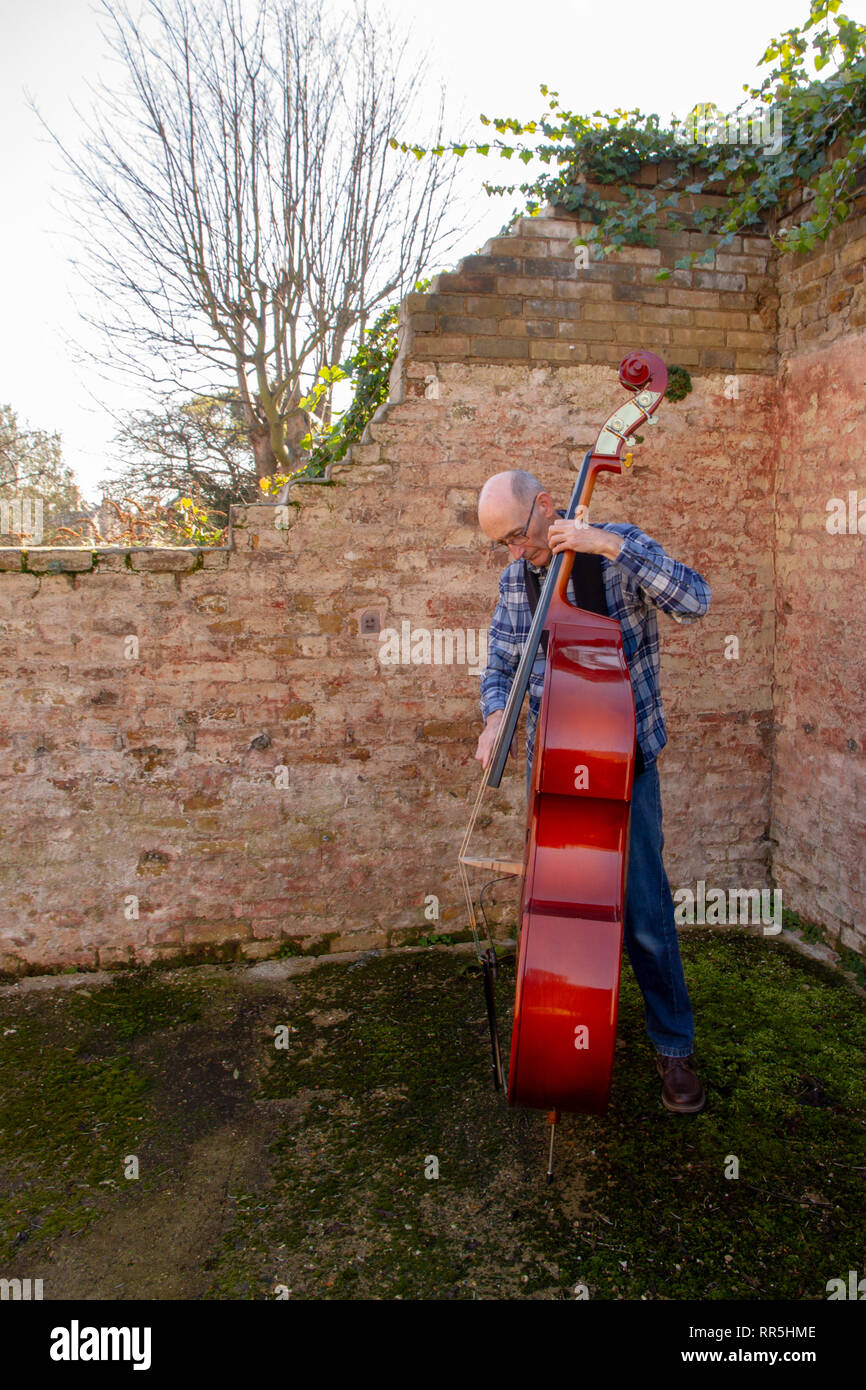 An older man playing double bass in a ruined building Stock Photo