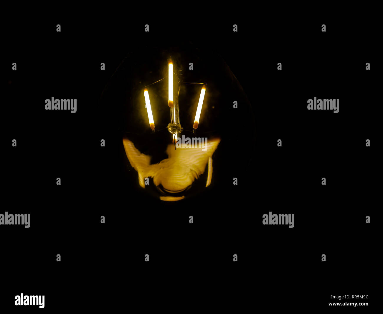 lightbulb on dark background with bright yellow shining wire Stock Photo