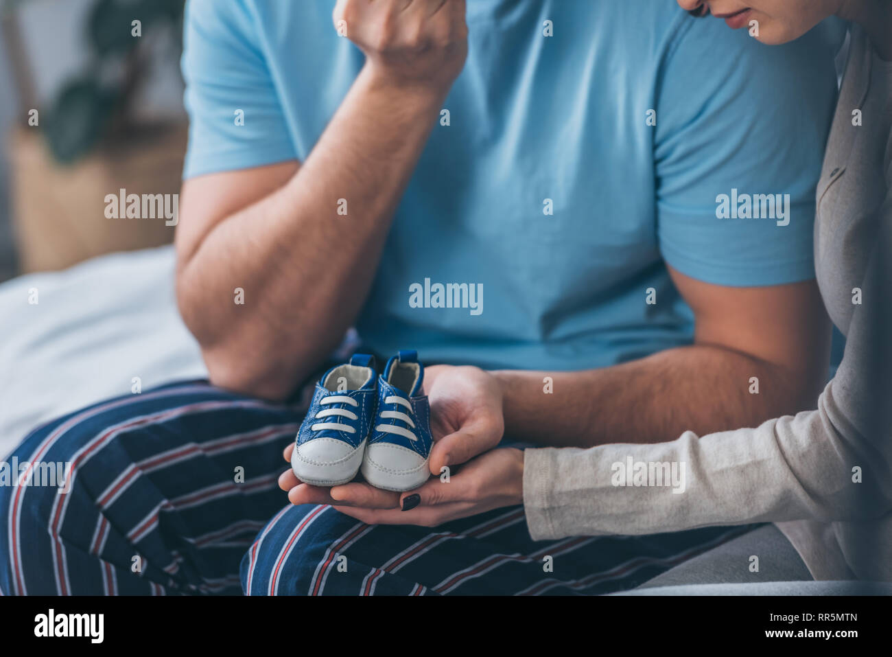 cropped view of parents holding baby shoes at home Stock Photo