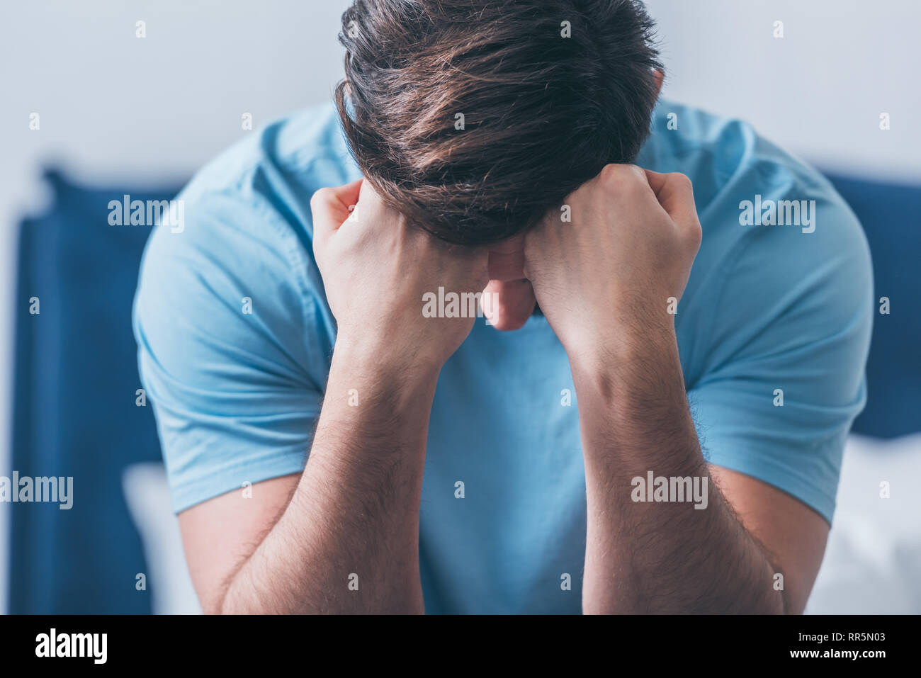 selective focus of grieving man covering face with hands and crying at home Stock Photo