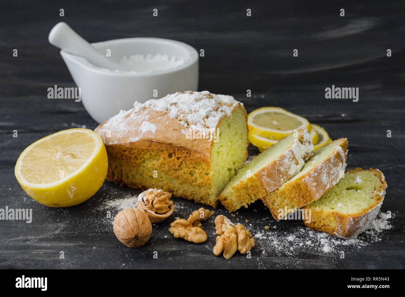 Mint cake on black surface with lemon, nuts, powdered sugar. Stock Photo