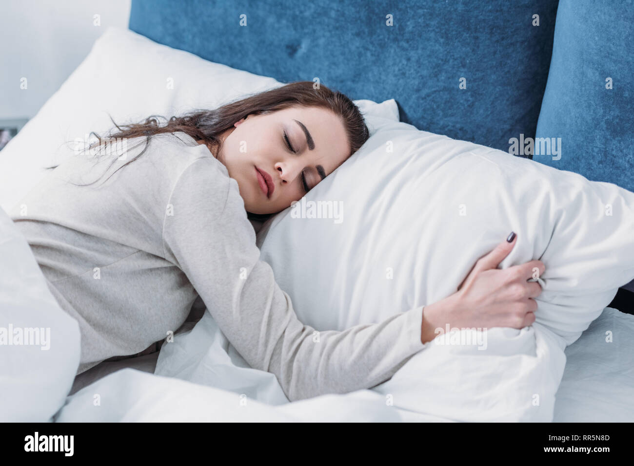 beautiful tired woman hugging pillow and sleeping in bed at home