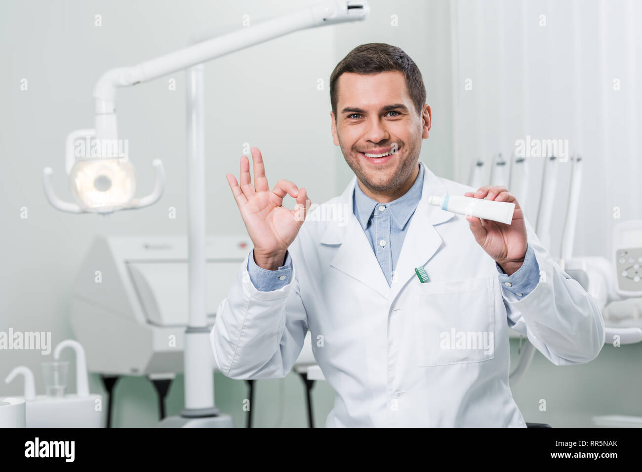 dentist holding toothpaste and showing ok sign in dental clinic Stock Photo Alamy