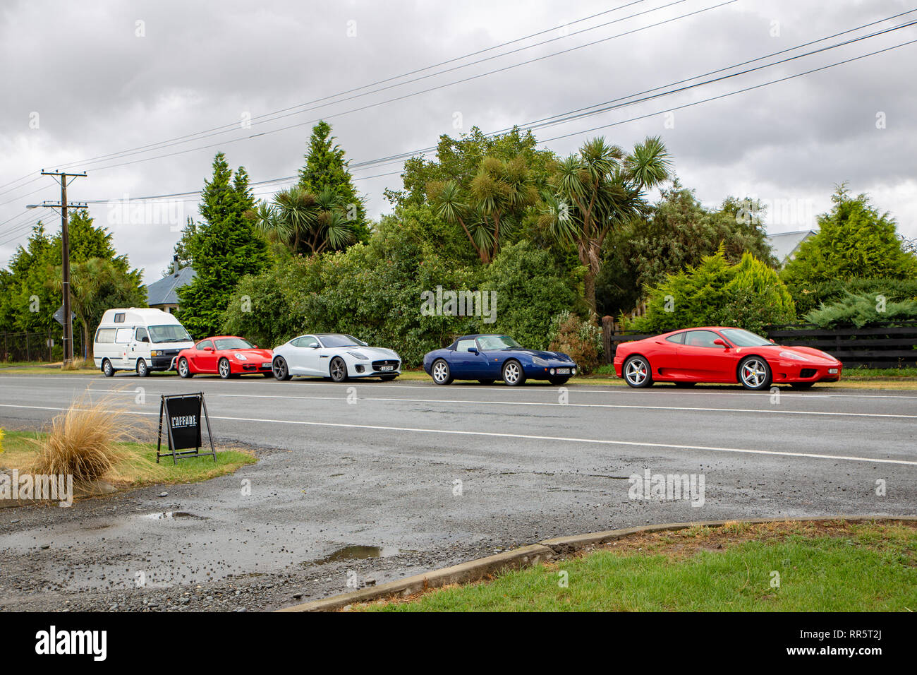 Springfield, Canterbury, New Zealand, February 24 2019: A tourist's van and luxury cars parked along a main rural highway outside a cafe Stock Photo