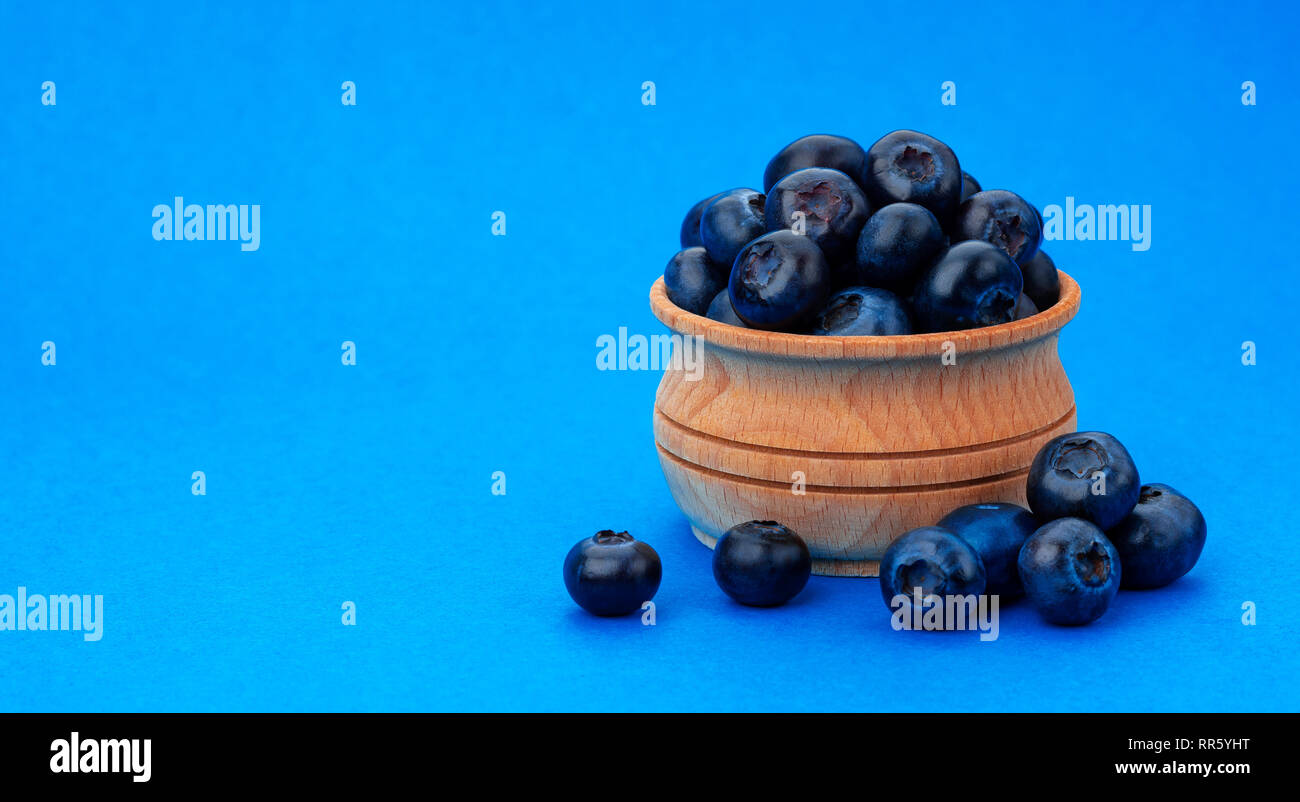 Blueberry isolated on blue background with copy space. A pile of fresh blueberries in a wooden bowl Stock Photo