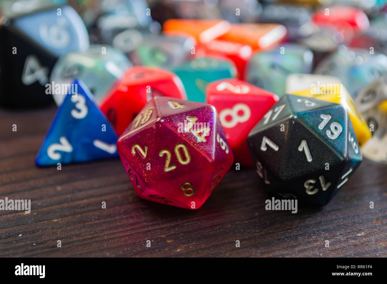 various colorful polyhedral game dice on a table with a 20 and a one in the foreground Stock Photo