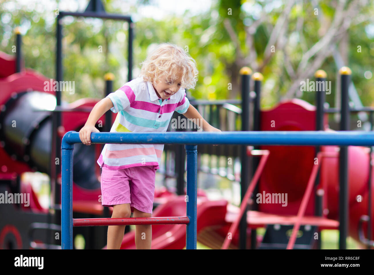 Child on monkey bars. Kid at school playground. Little boy hanging on