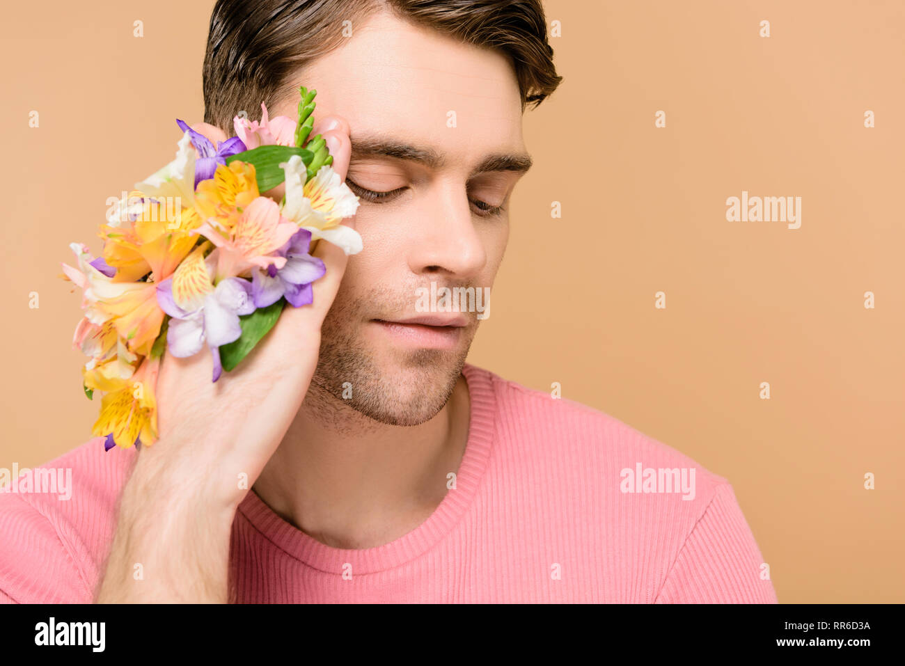handsome man with alstroemeria flowers on hand isolated on beige Stock Photo