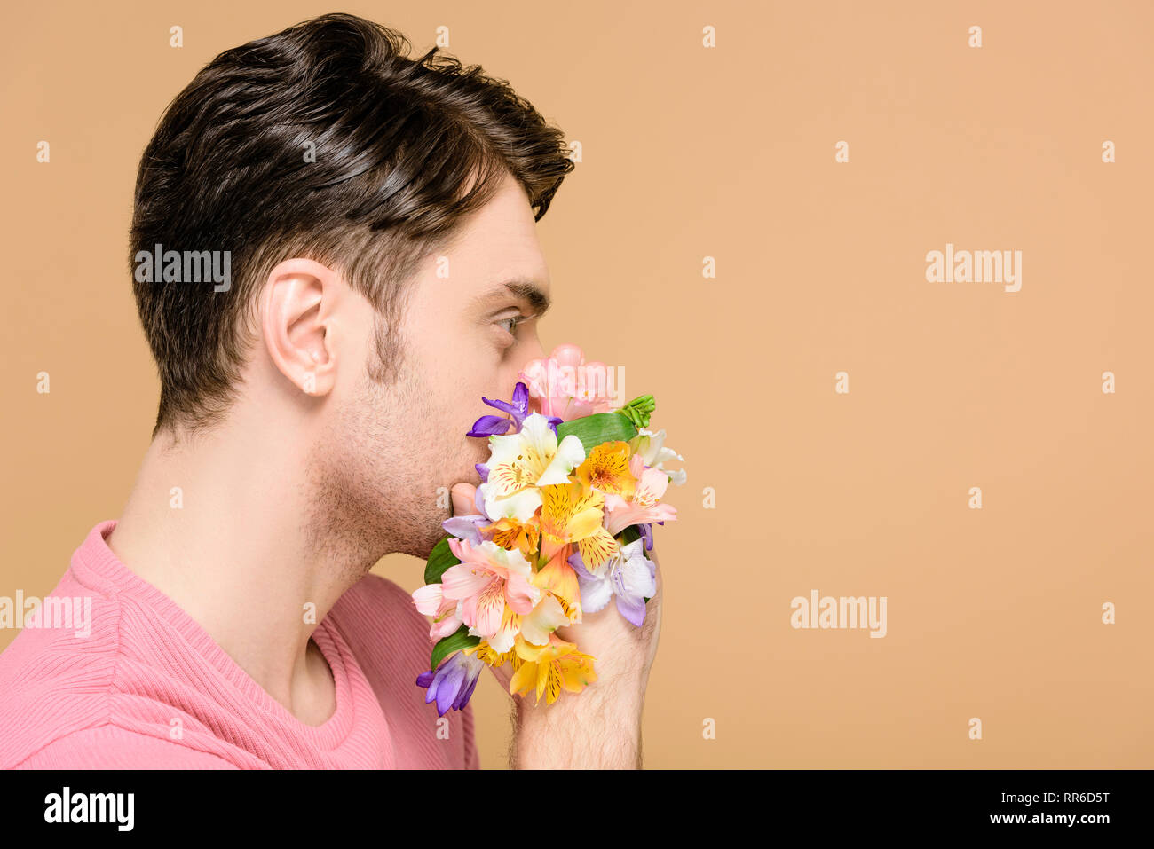 man covering mouth with flowers isolated on beige Stock Photo