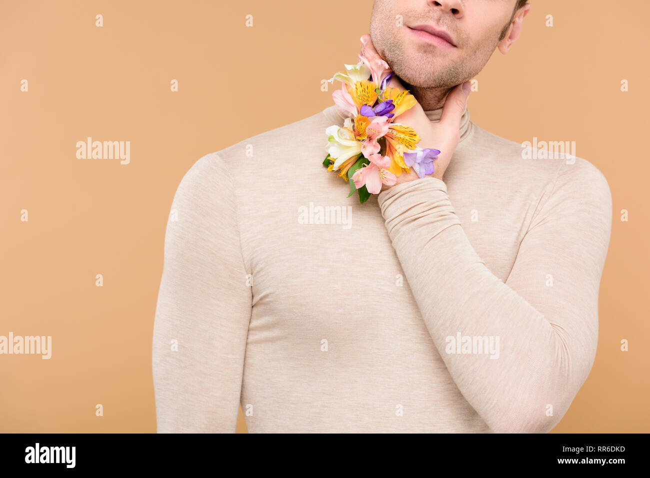 cropped view of man with alstroemeria flowers on hand touching neck isolated on beige Stock Photo