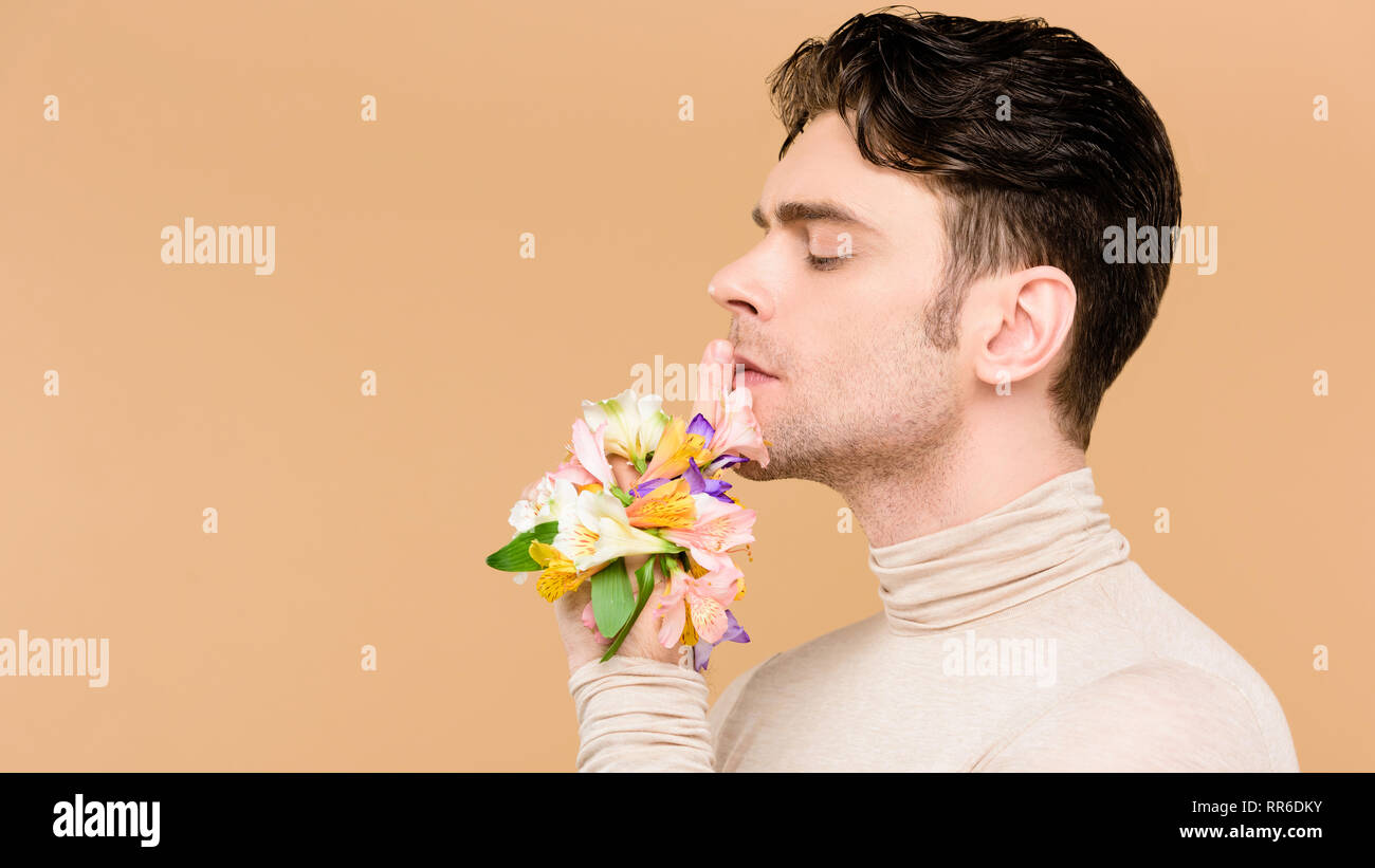 side view of handsome man with alstroemeria flowers on hand showing hush sign isolated on beige Stock Photo