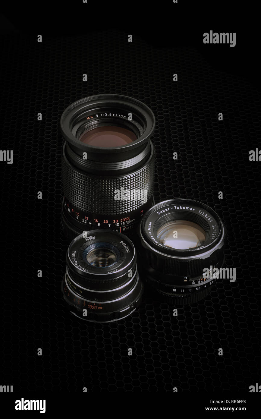 Three vintage M42 lenses against a black background, vertical apsect. Stock Photo