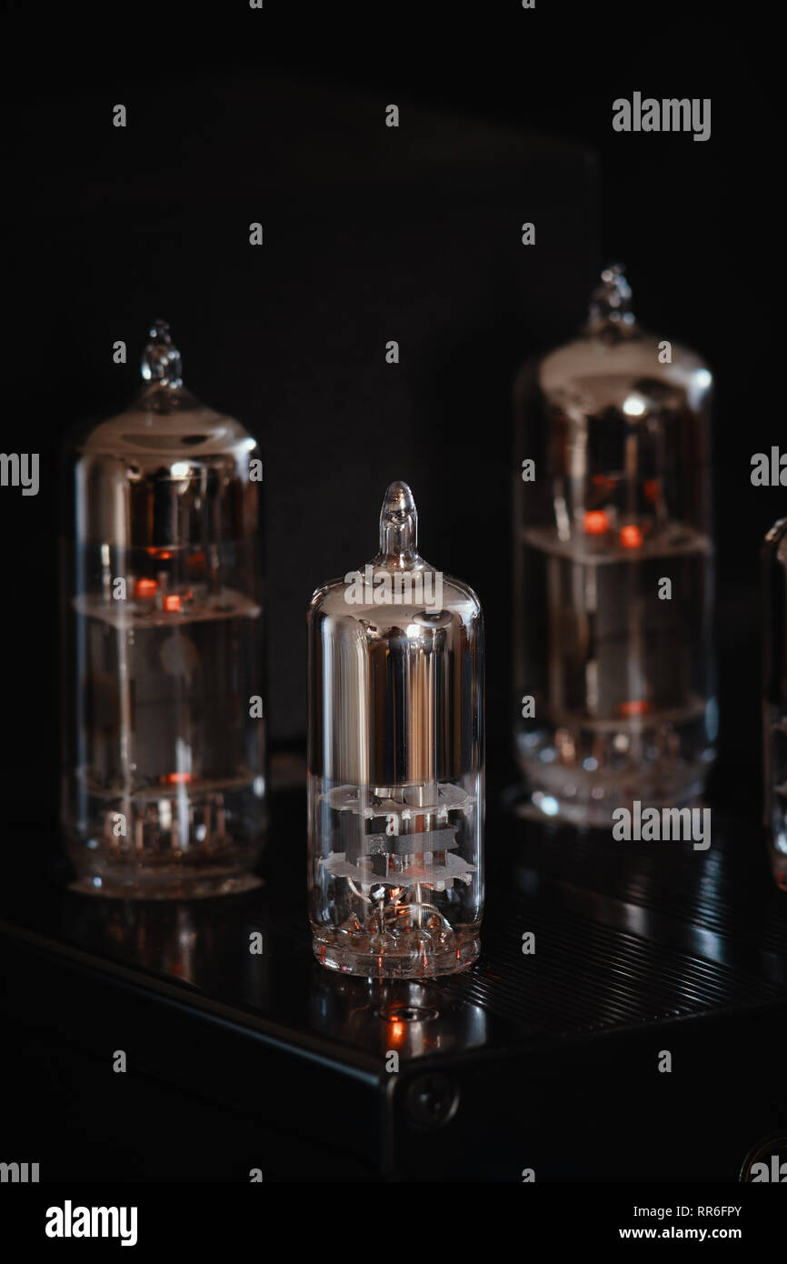 Headphone amplifier with three dominant glowing vacuum tubes / valves against a black background
