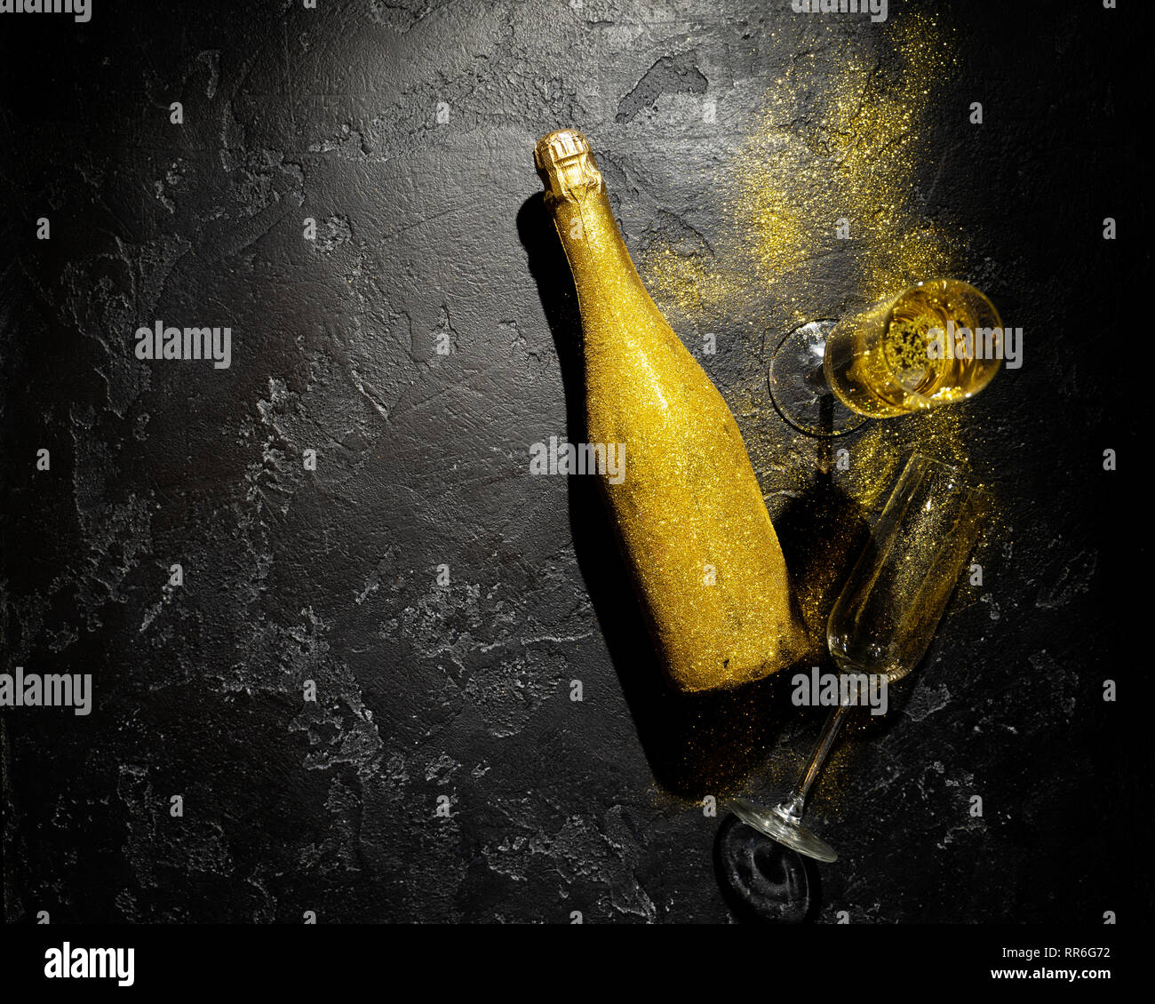 Romantic image of golden champagne bottle, two wine glasses on black