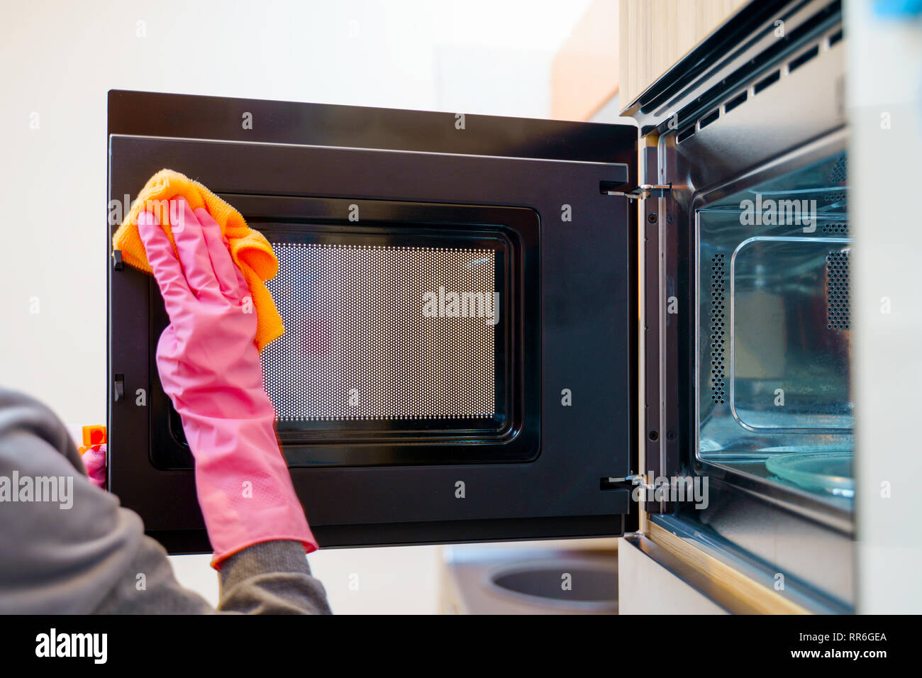 Image of woman hands in rubber gloves washing microwave. Stock Photo