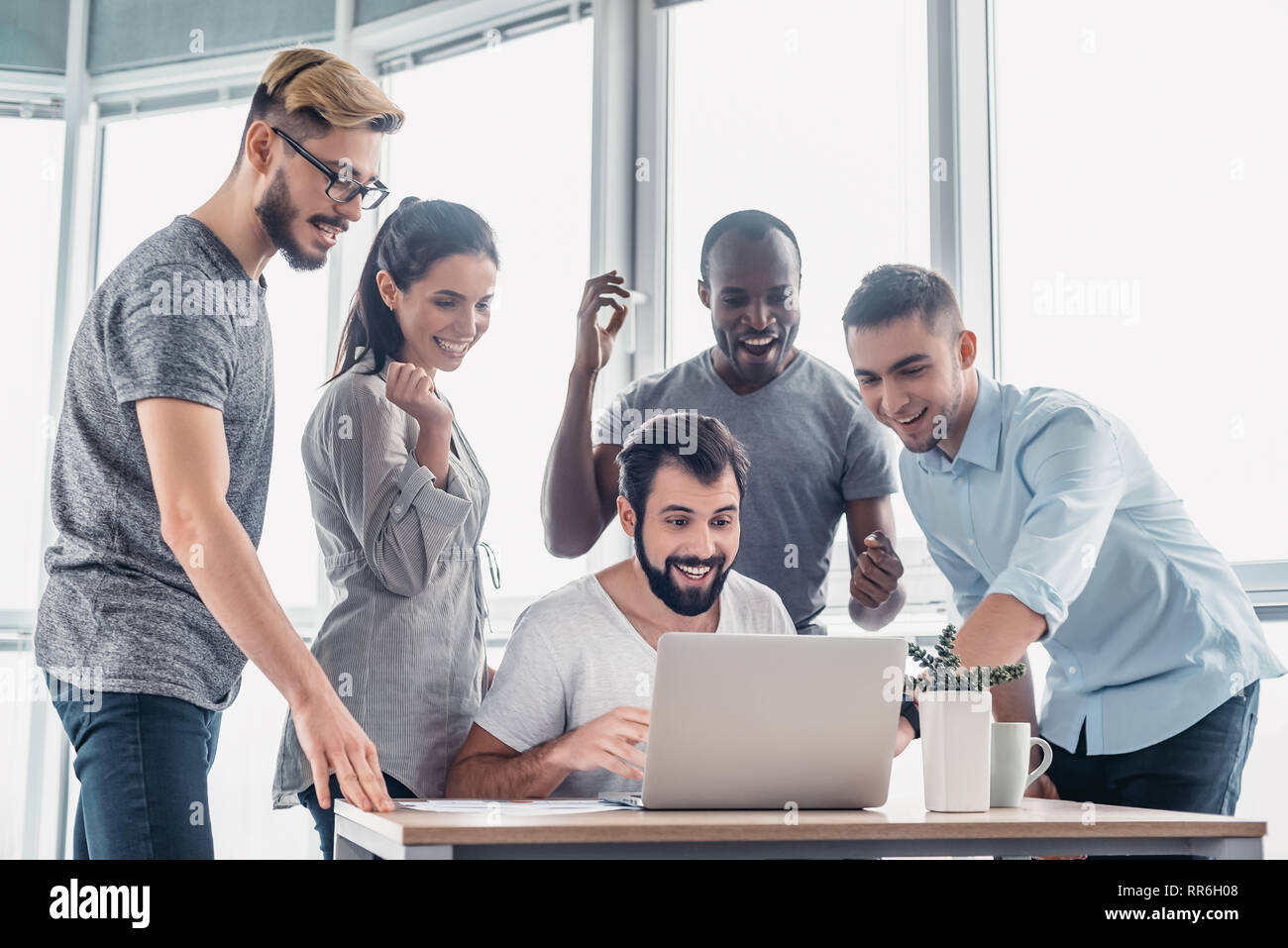 Five diverse business people talking together over a laptop while working in office boardroom. Business team working on their business project together at office. Concept of success Stock Photo