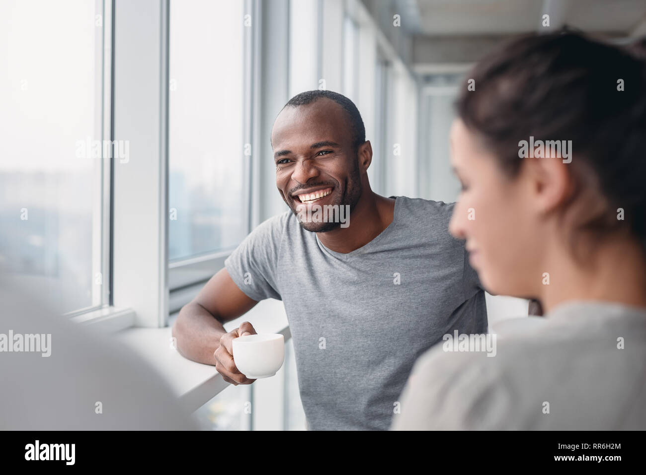 Happy African American employee have fun at coffee break in office, excited male worker laugh at colleague joke, multiracial co-workers smile negotiating. Teambuilding concept Stock Photo