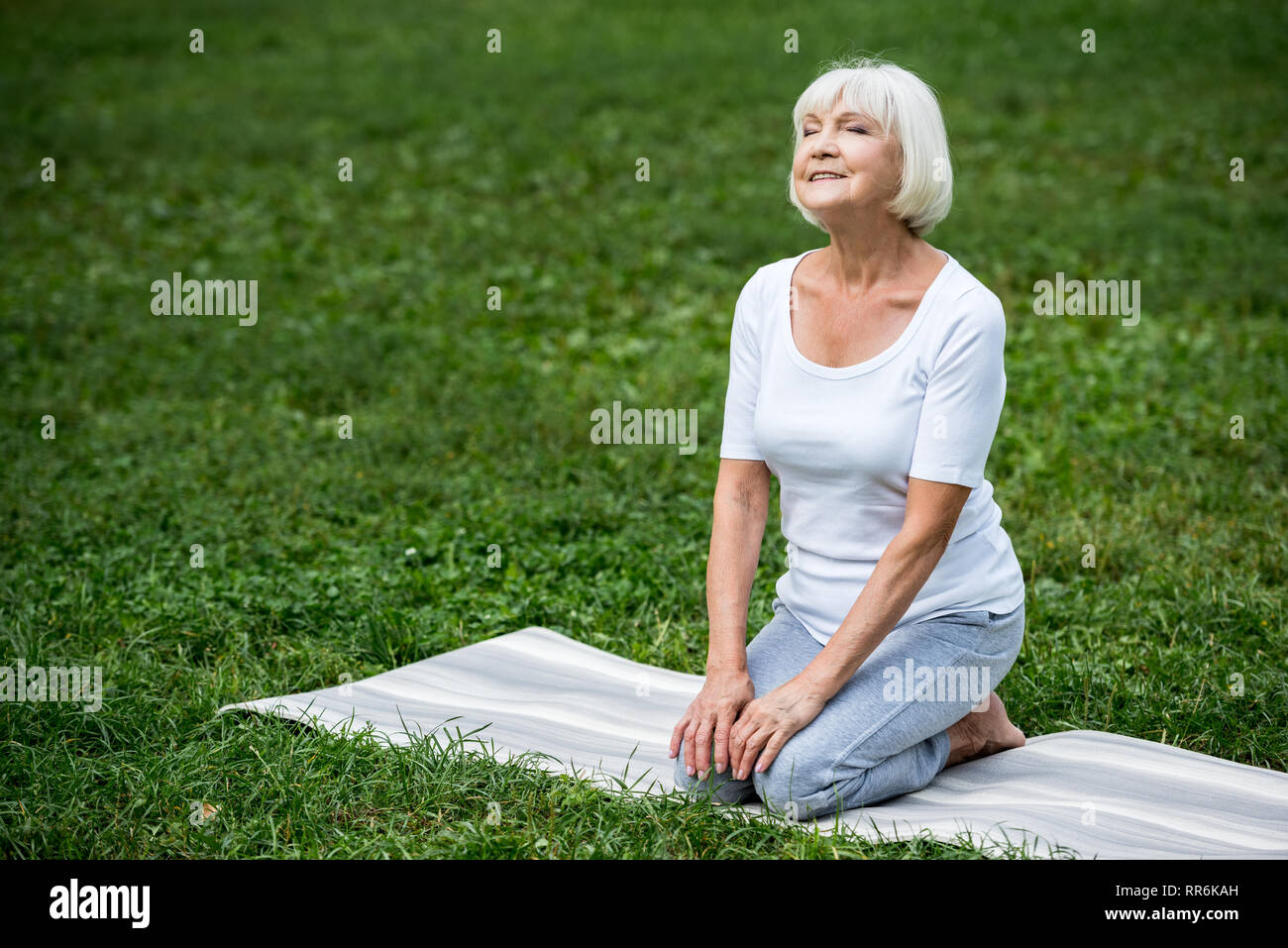 happy senior woman sitting in meditation pose with hands on knees and ...