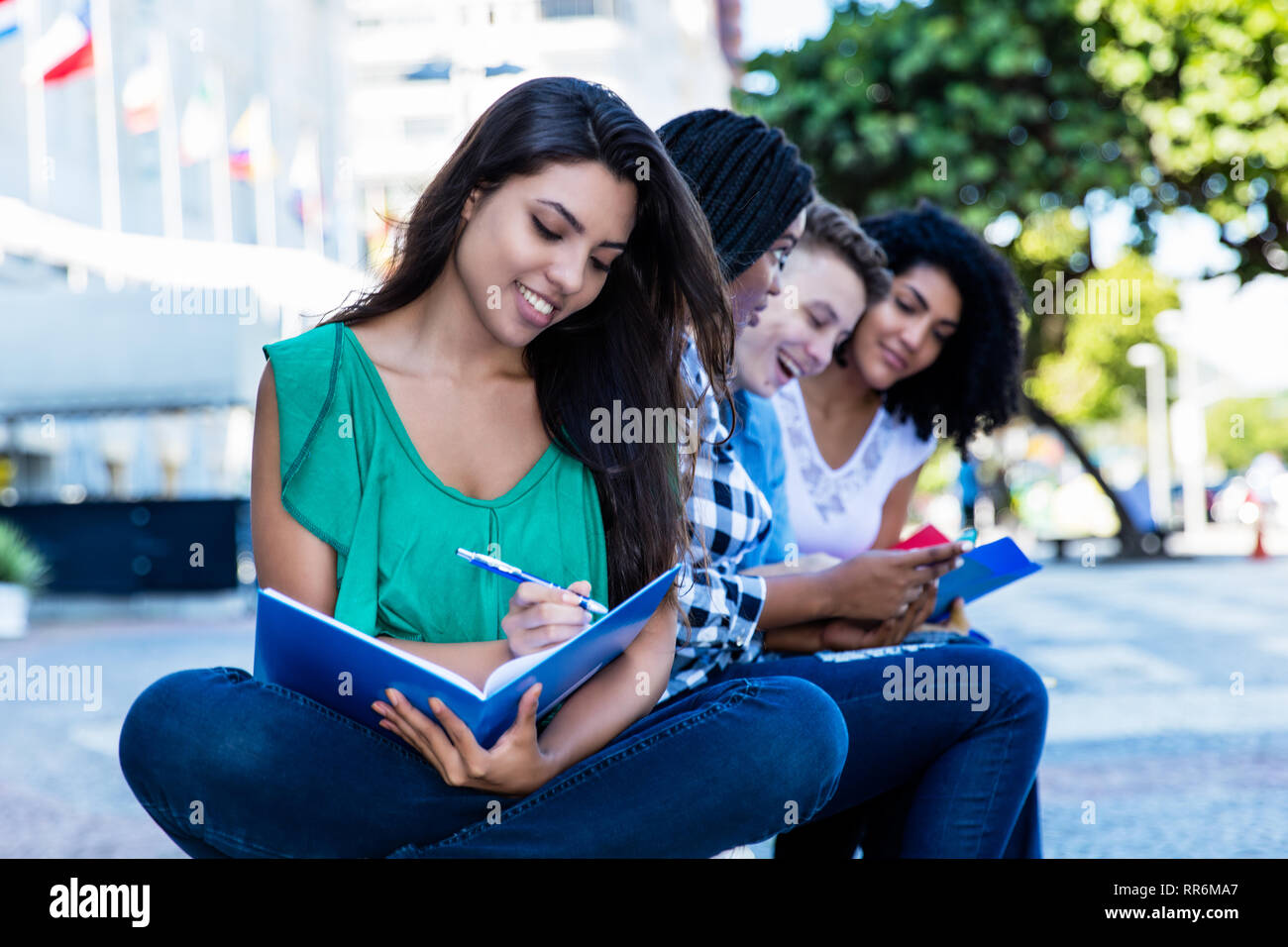 Happy learning latin american female student with group of international students outdoor in the summer in the city Stock Photo