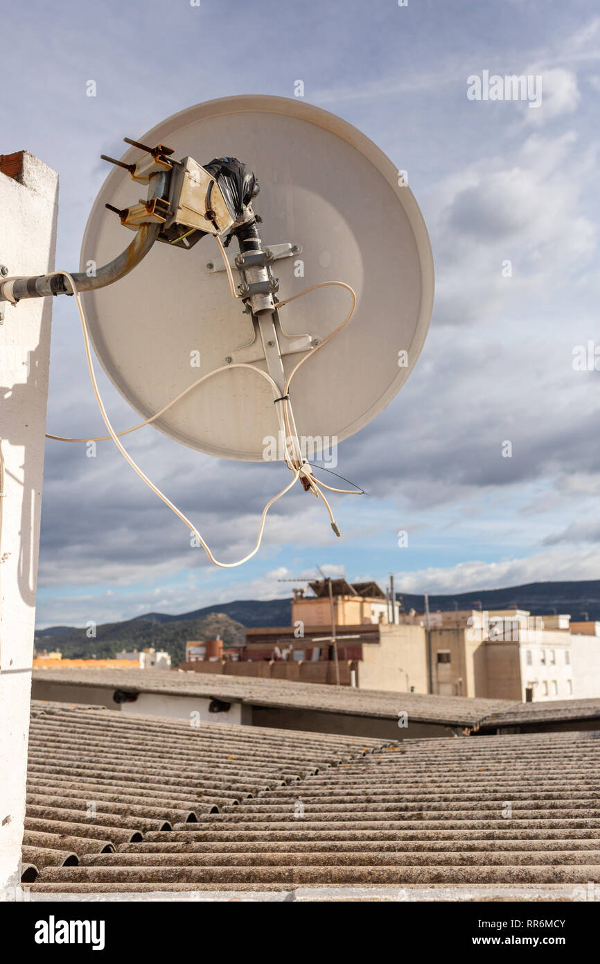Old satellite dish on apartament building in Spain. Sunny cloudy day. Stock Photo