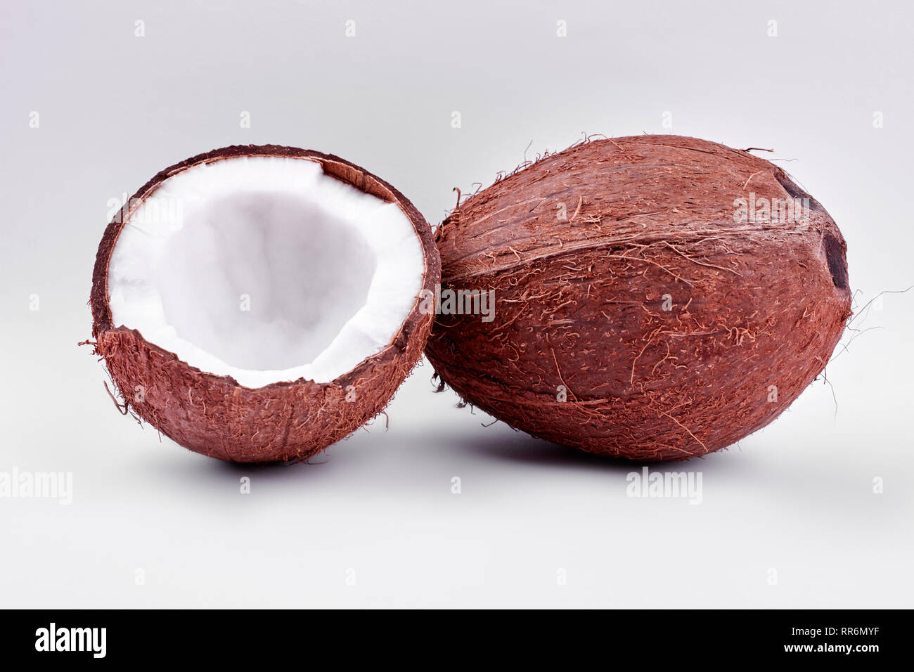 Whole and cracked coconuts on light background Stock Photo Alamy
