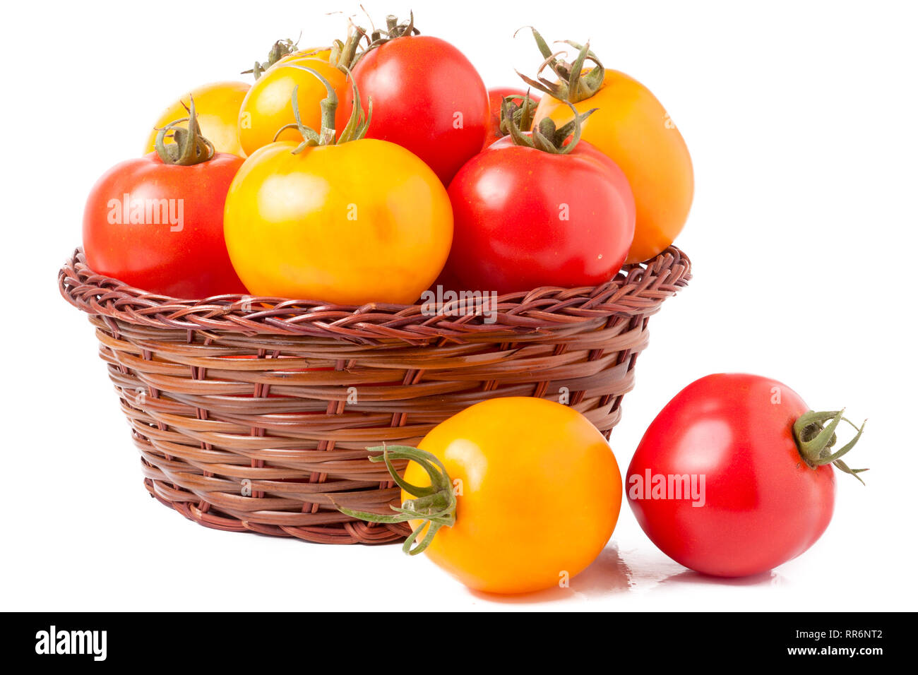 red and yellow tomatoes in a wicker basket isolated on white background ...