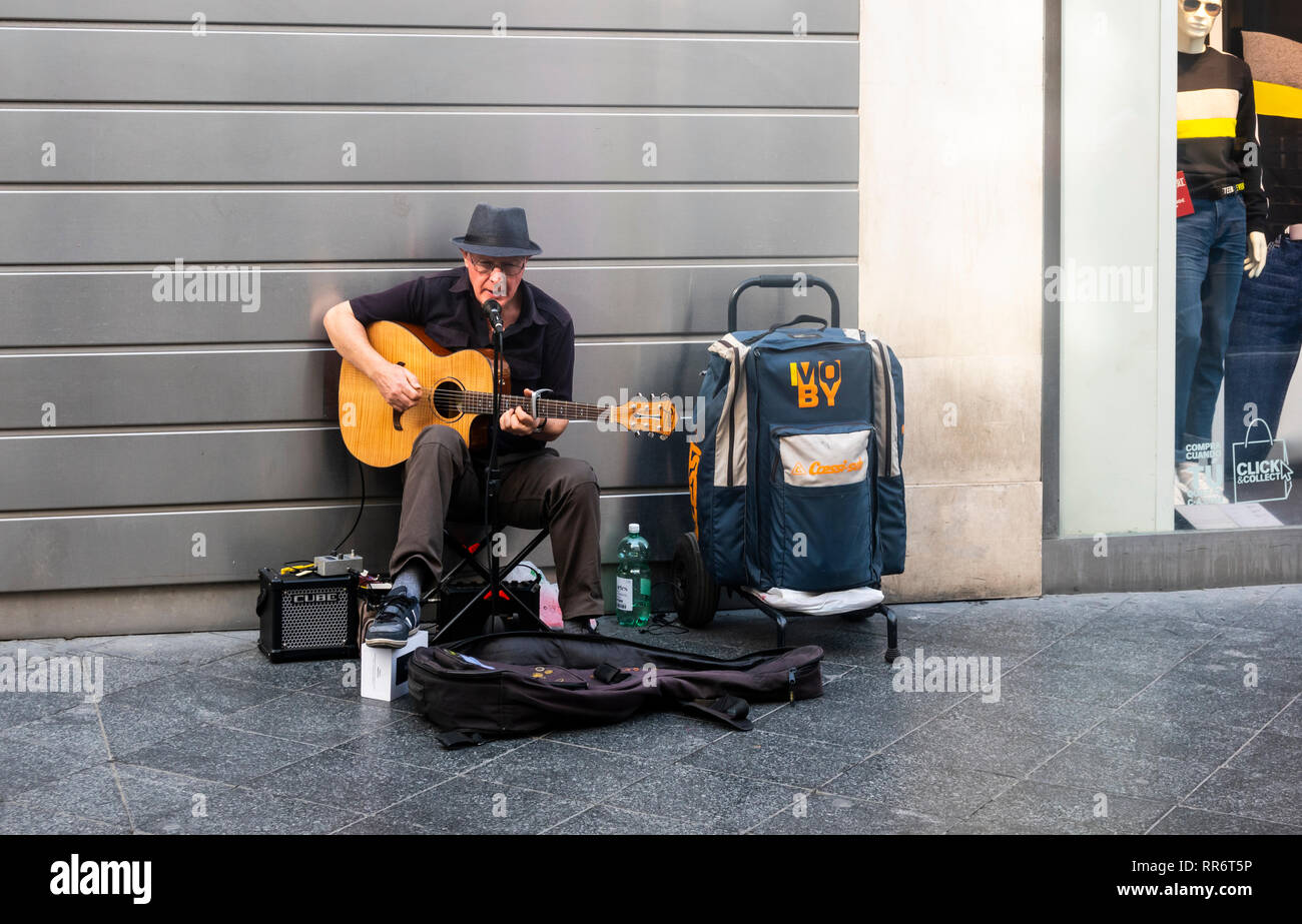 British busker singing and playing guitar on a shopping street in Seville, Spain Stock Photo