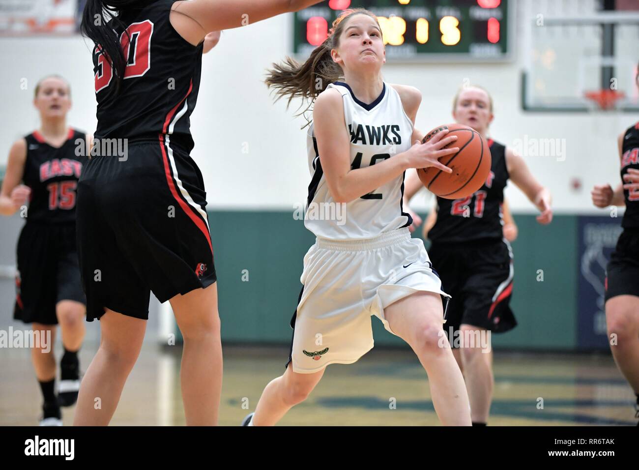 Player driving through the paint and on a defending opponent on her way to scoring two points. USA. Stock Photo