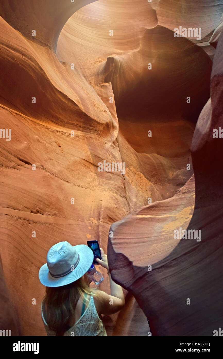 Tourist woman with hat taking mobile photo at Antelope canyon, Arizona. Adventure tour concept. Stock Photo