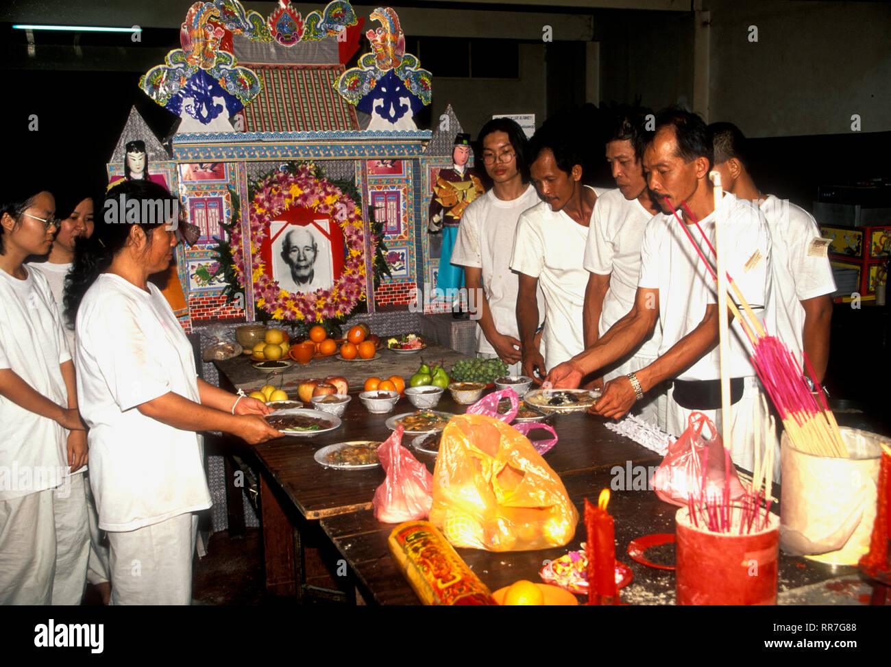 Family relatives observe Chinese funeral obsequies in Malacca, Malaysia with offerings of fruit and incense for the departed. Stock Photo
