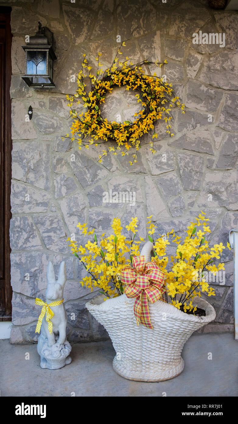 Forsythia wreath and basket with an Easter bunny on a front porch