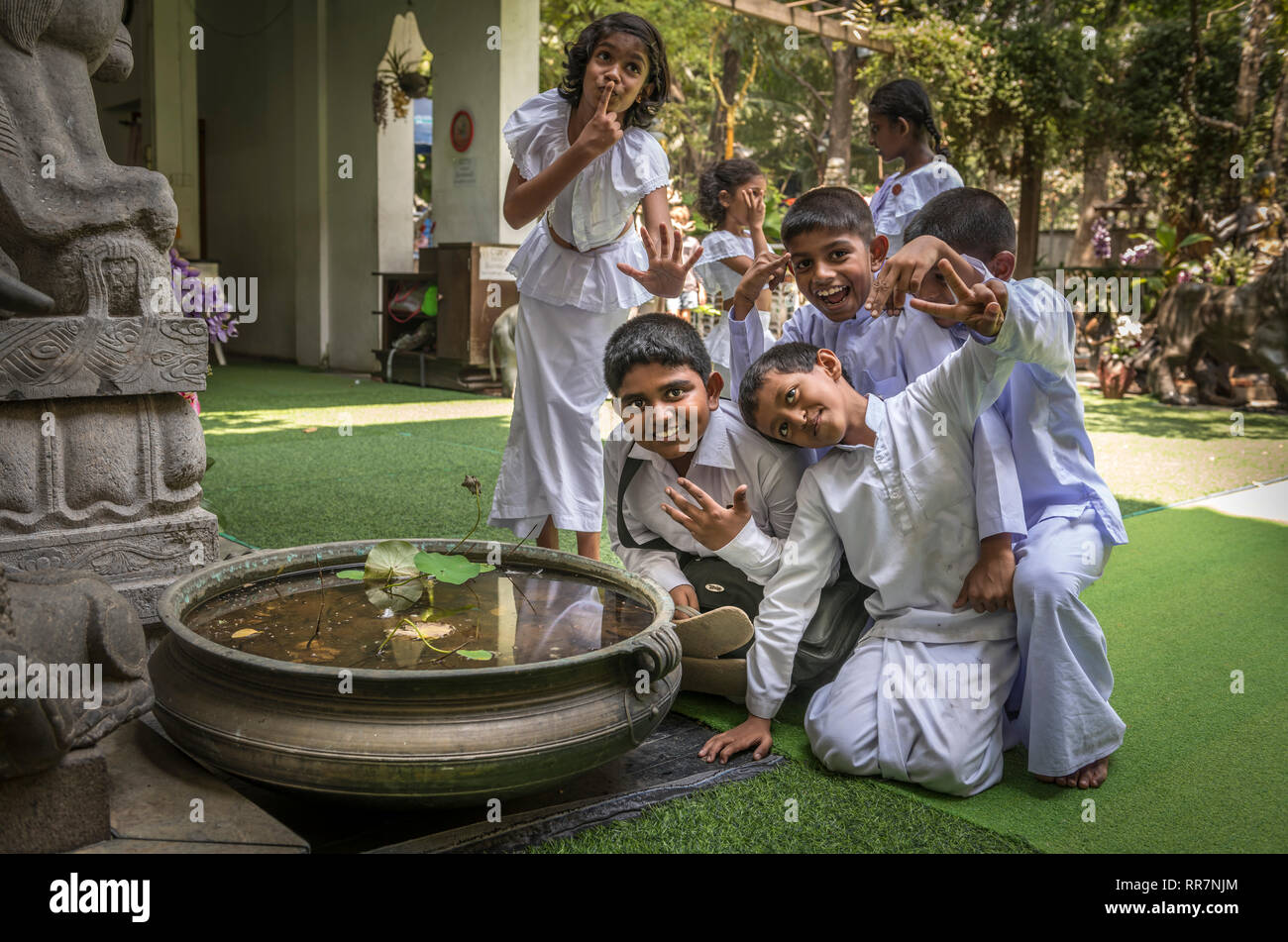 Children take time out from Sunday School to pose for the camera at the famous Gangaramaya Buddhist Temple in Colombo Sri Lanka. Stock Photo