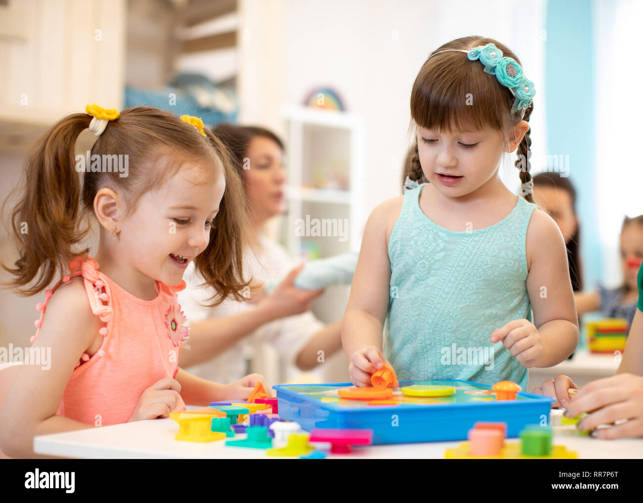 Children playing with developmental toys at table in kindergarten Stock