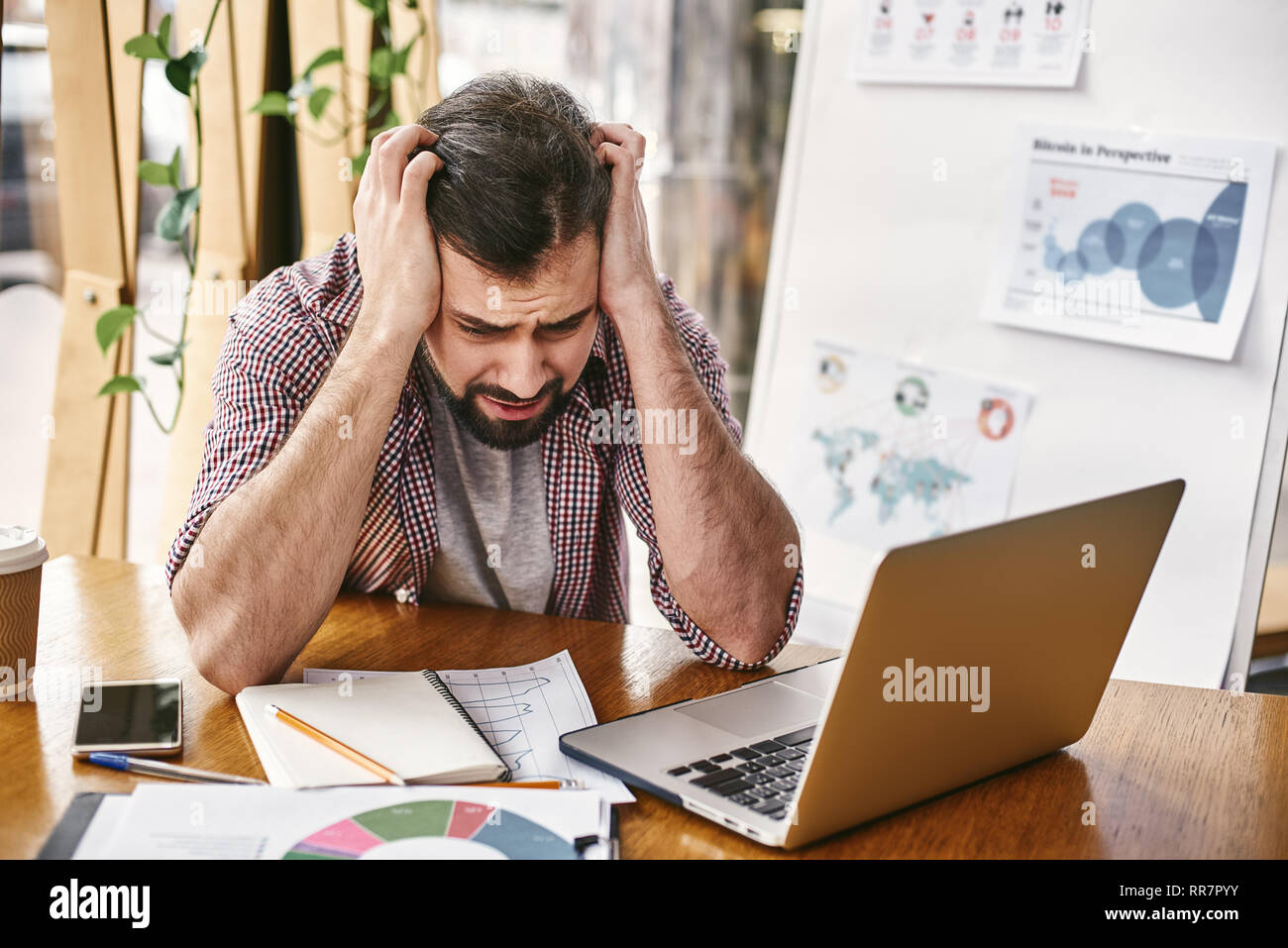 Stressed male employee having computer problem, working in creative office, man experiencing gadget troubles, trying to stay calm, managing emotions, angry worker witness pc breakup Stock Photo