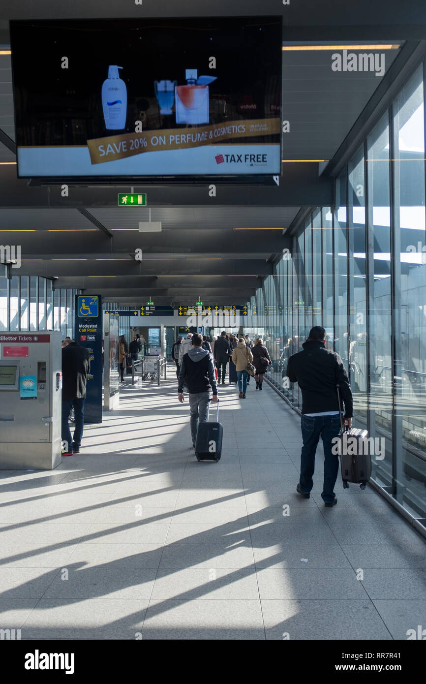 Passengers pulling luggage from Copenhagen airport terminal building