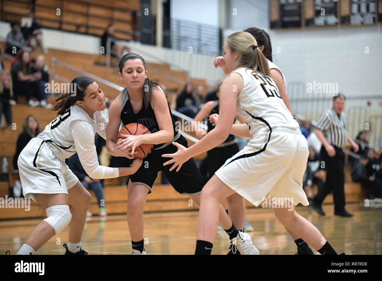 Player clings to the basketball between opponents to force a jump ball