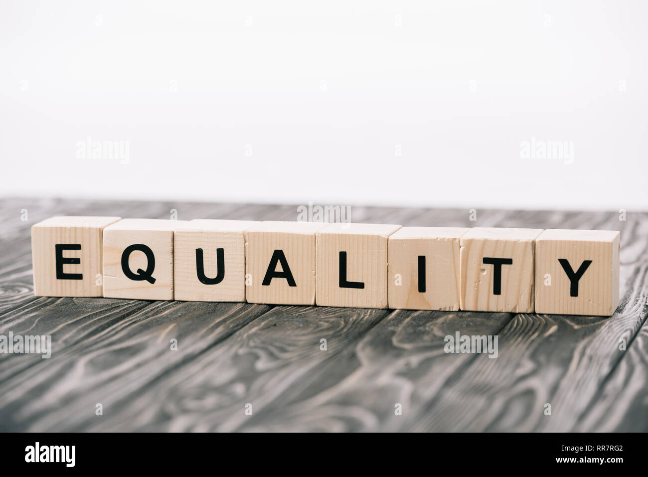 equality lettering made from alphabet cubes on wooden table on white Stock Photo