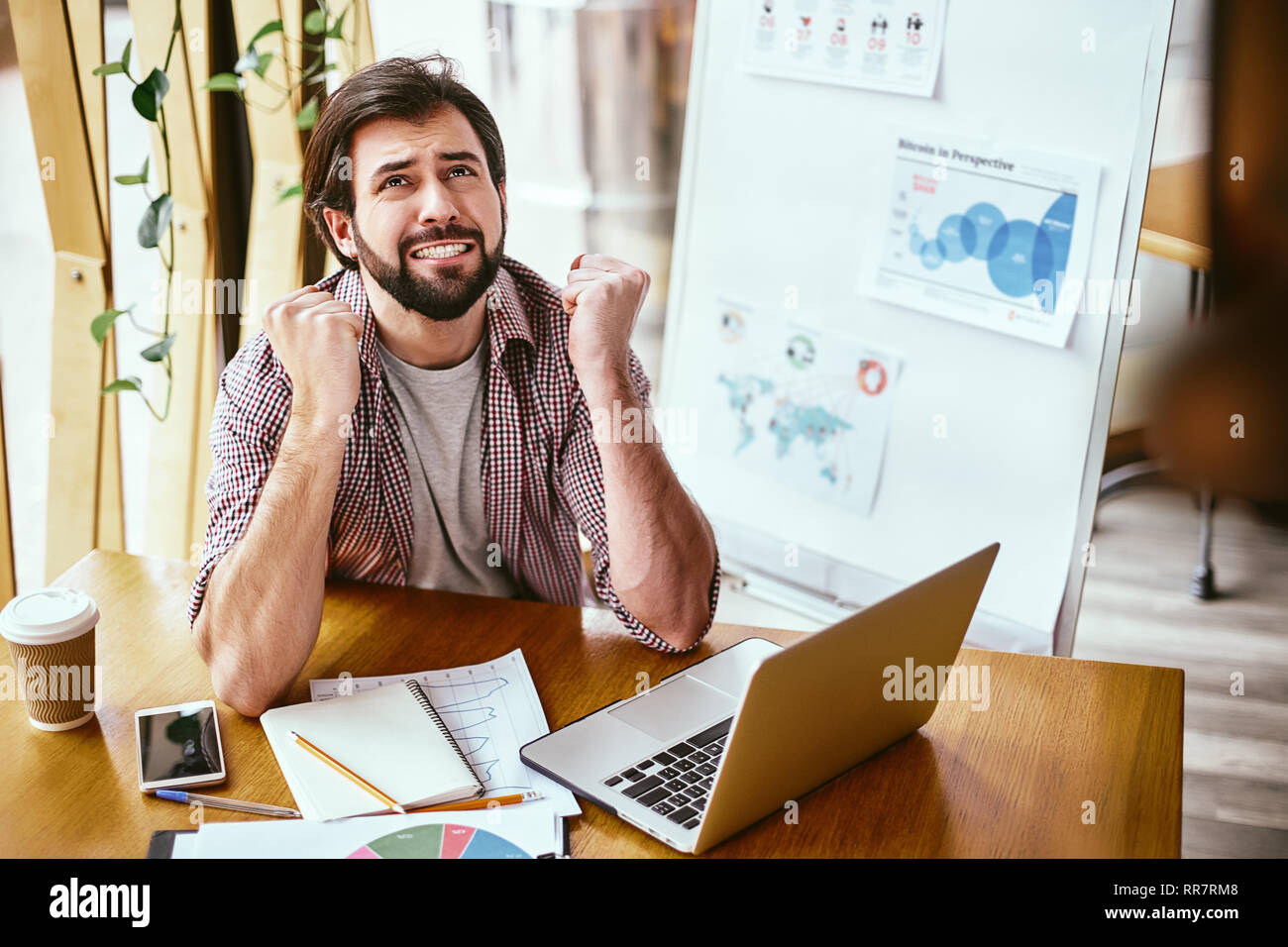 Emotional businessman sitting with a laptop computer waiting in tension for online result, nervous man, office employee clenching fists feeling enthusiastic cheering, supporting, hope for win concept Stock Photo
