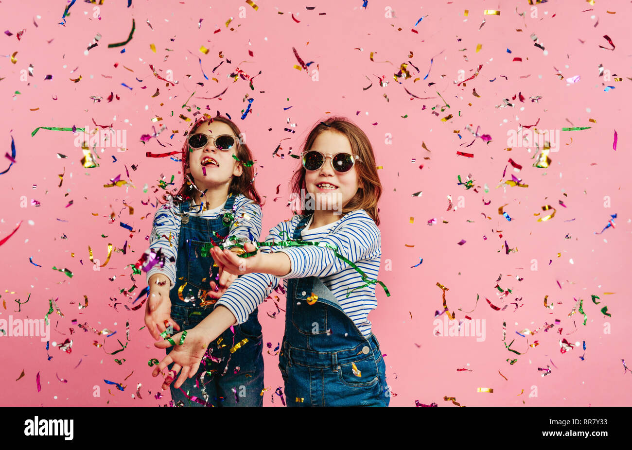 Stylish girls wearing fashion clothes and sunglasses throwing colorful