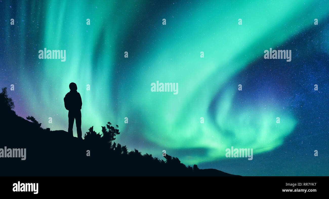 Aurora borealis and silhouette of a woman with backpack at night. Girl on  the hill, starry sky with northern lights. Sky with stars and polar lights  Stock Photo - Alamy
