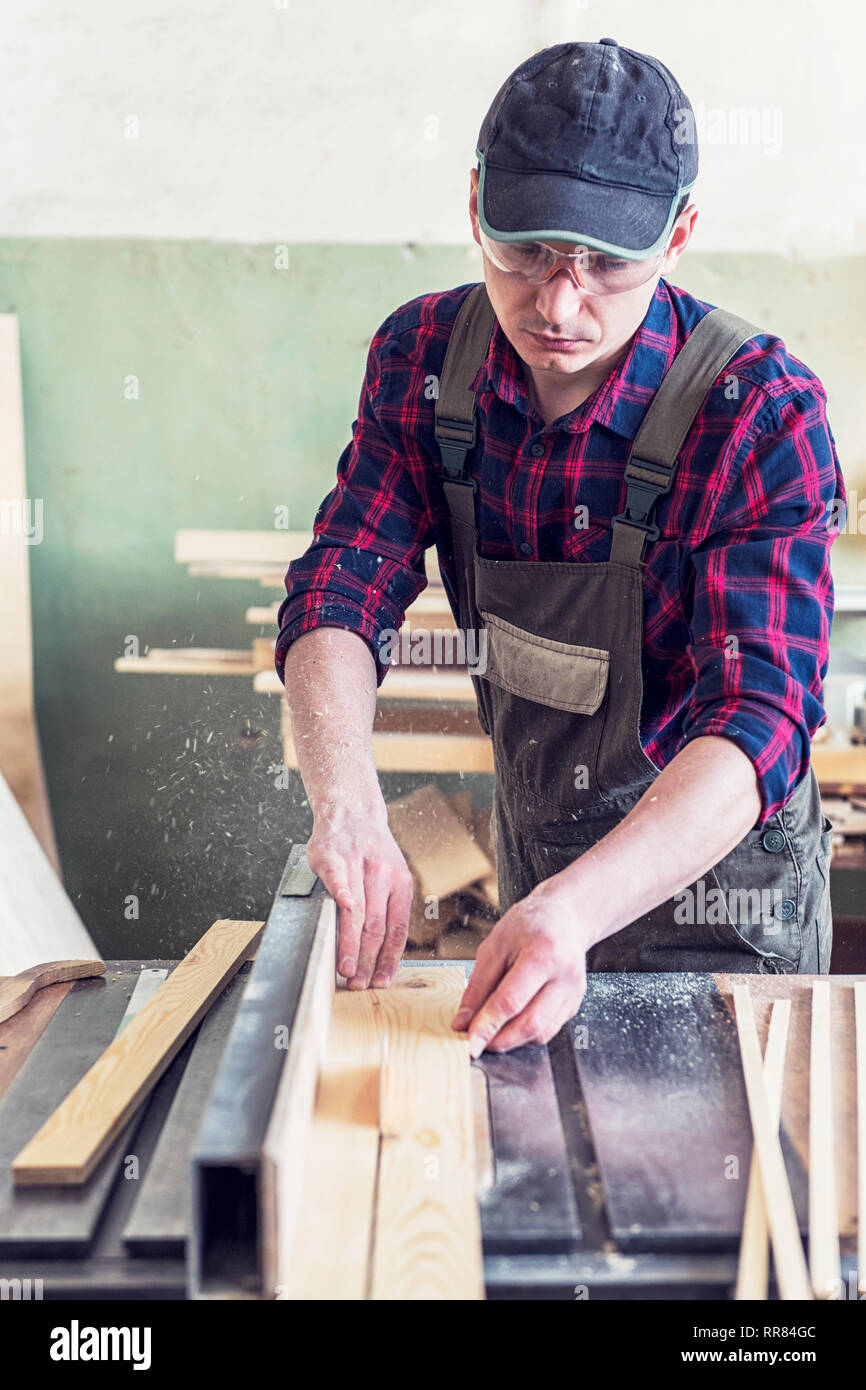 Construction worker cutting wooden board Stock Photo - Alamy