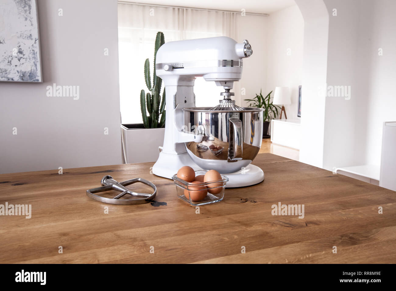 https://c8.alamy.com/comp/RR8M9E/white-kitchen-machine-and-stand-mixer-on-a-wooden-table-in-a-bright-design-apartment-RR8M9E.jpg