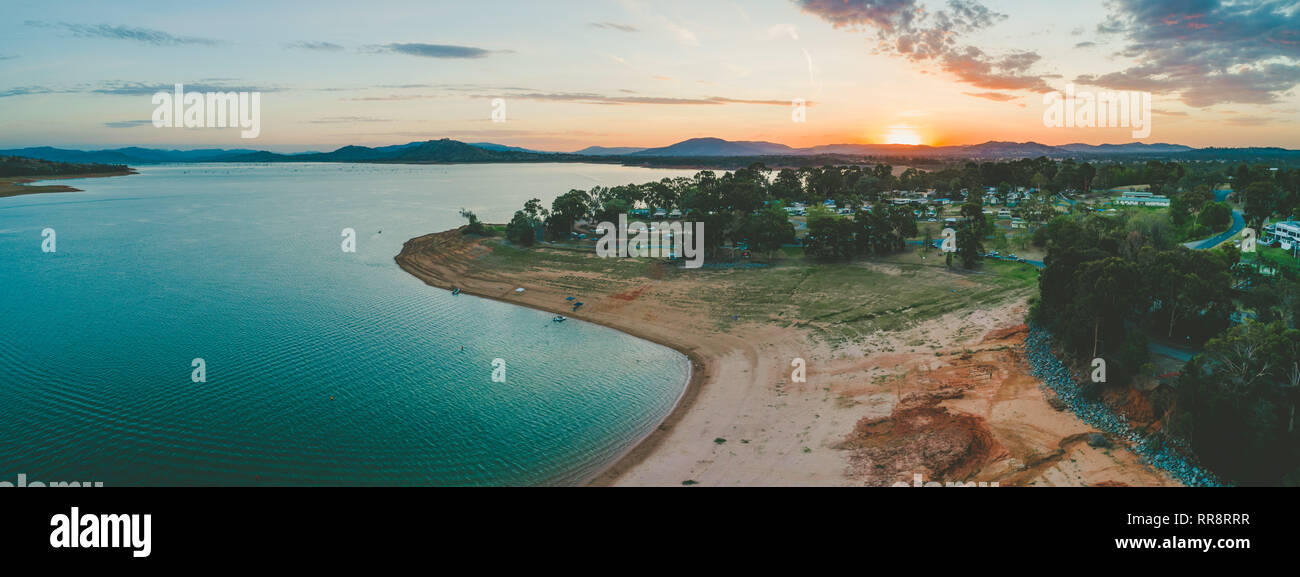 Sun disappearing behind mountains near Lake Hume Village - aerial panorama Stock Photo