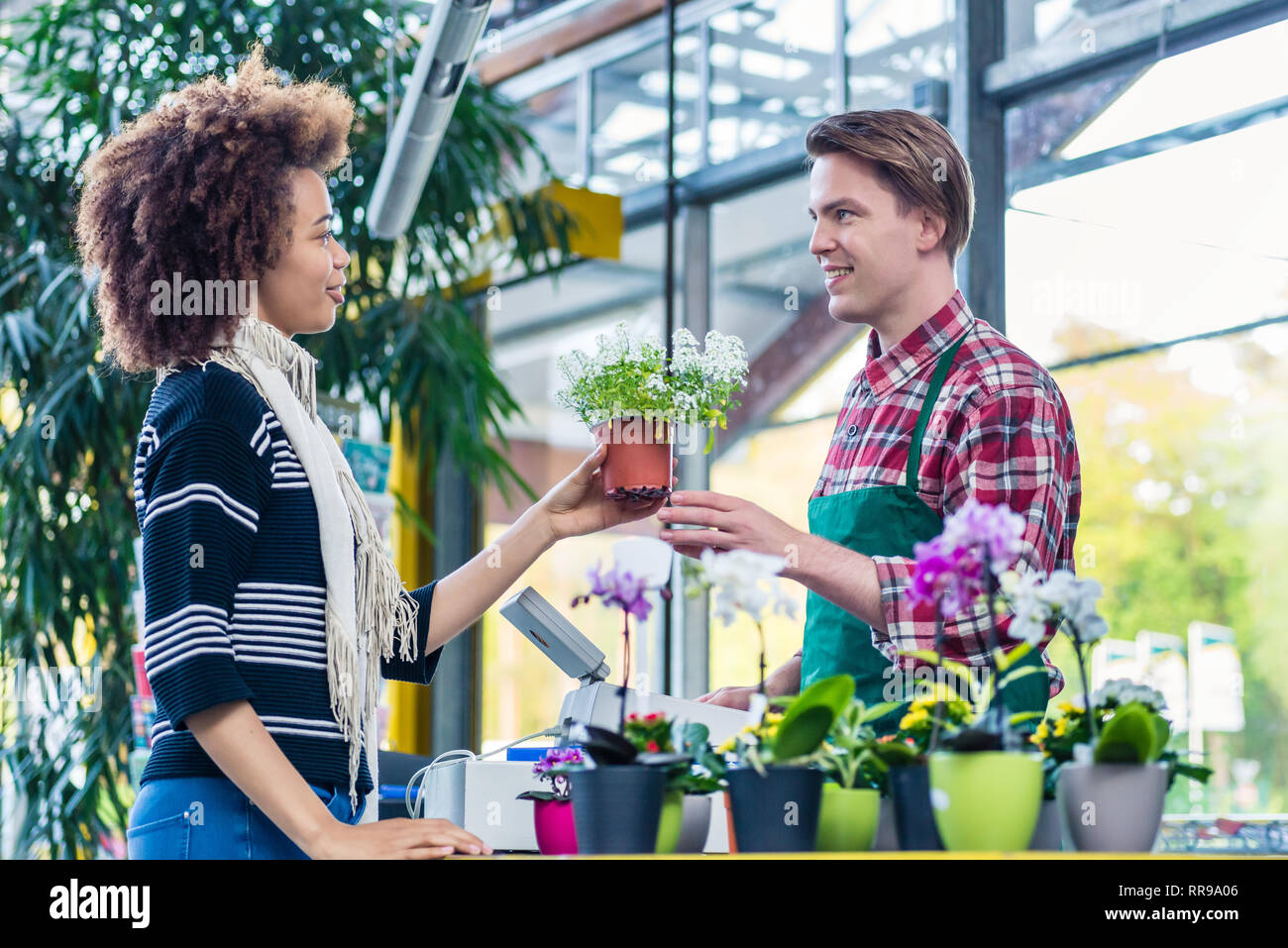 Man listening to a customer while working as a cashier in a modern flower shop Stock Photo
