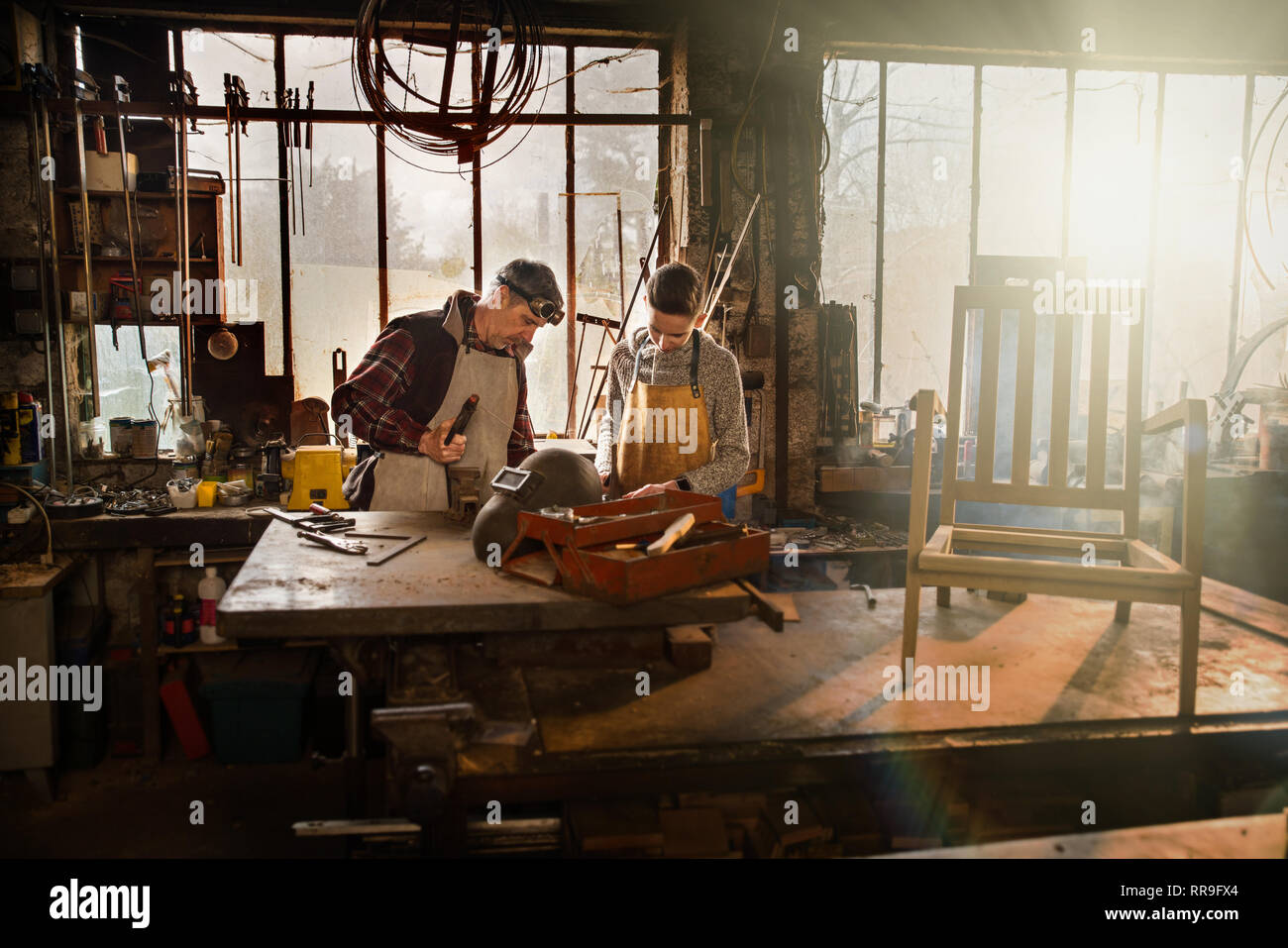 A craftsman in his workshop teaches his work to his apprentice Stock Photo