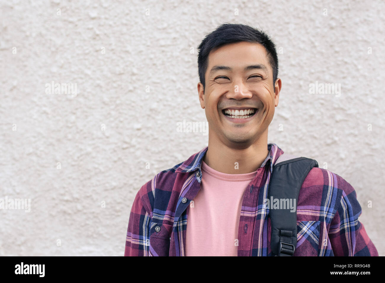 Cool Asian man standing outside in the city and laughing Stock Photo