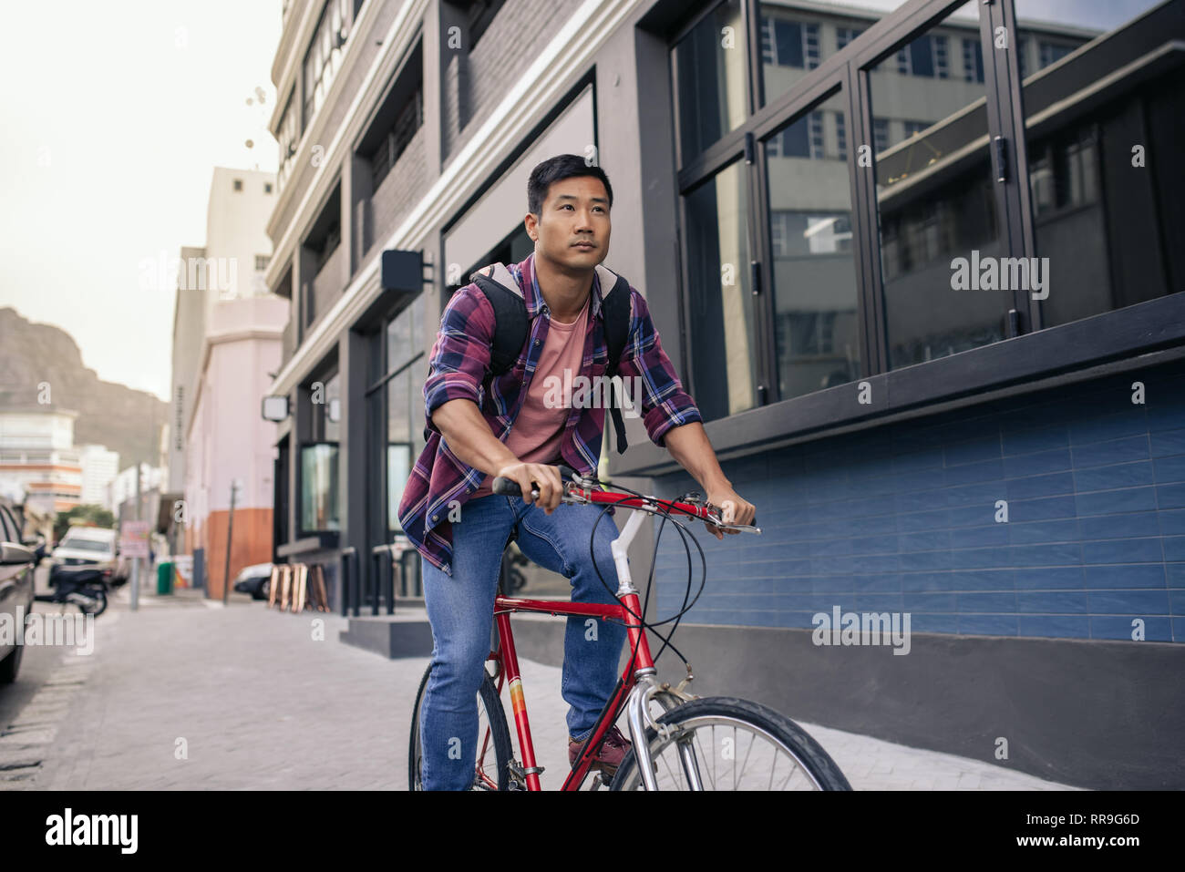 Young man riding his bicycle on a city sidewalk Stock Photo