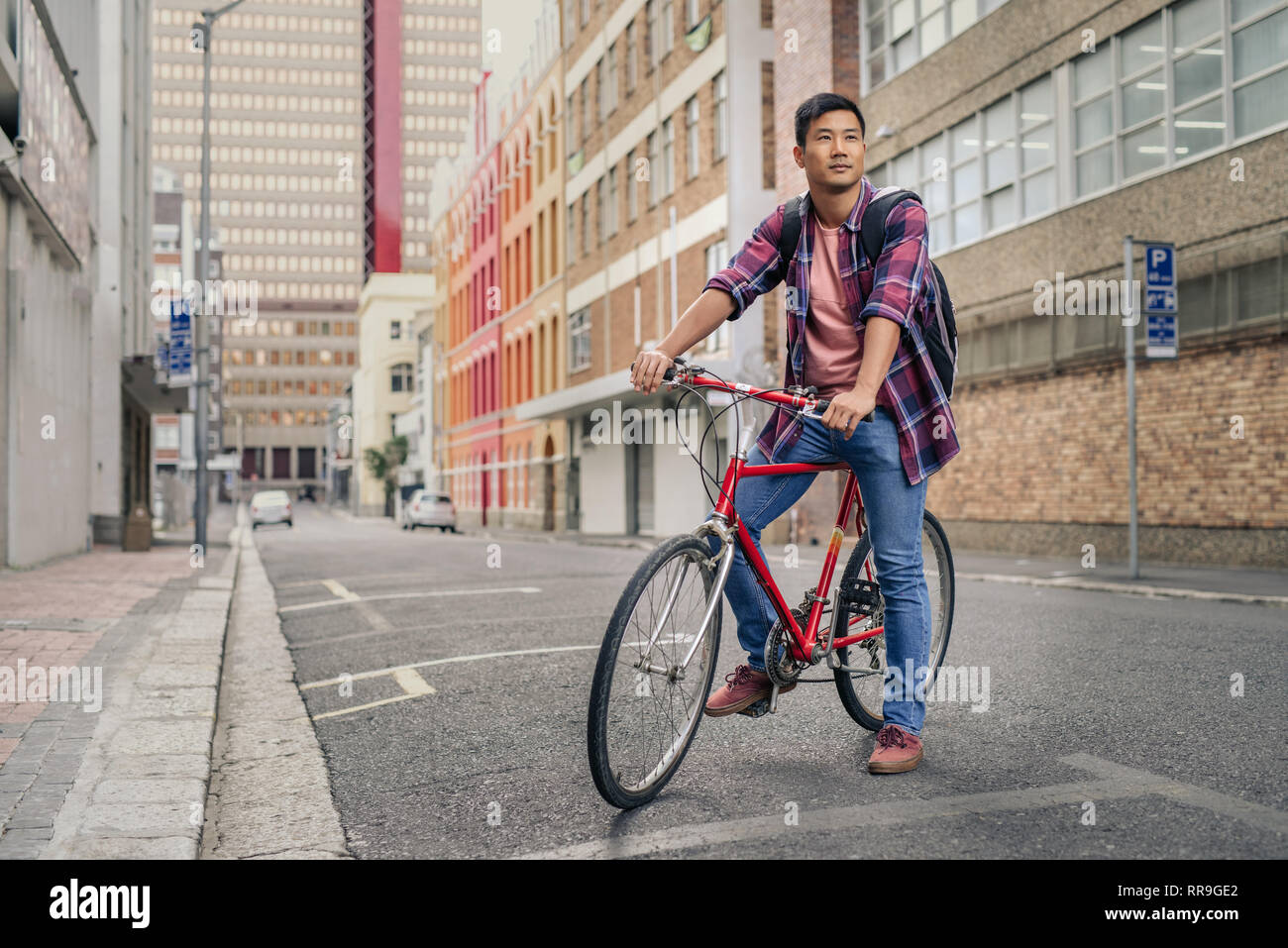 Young man sitting on his bicycle on a city street Stock Photo