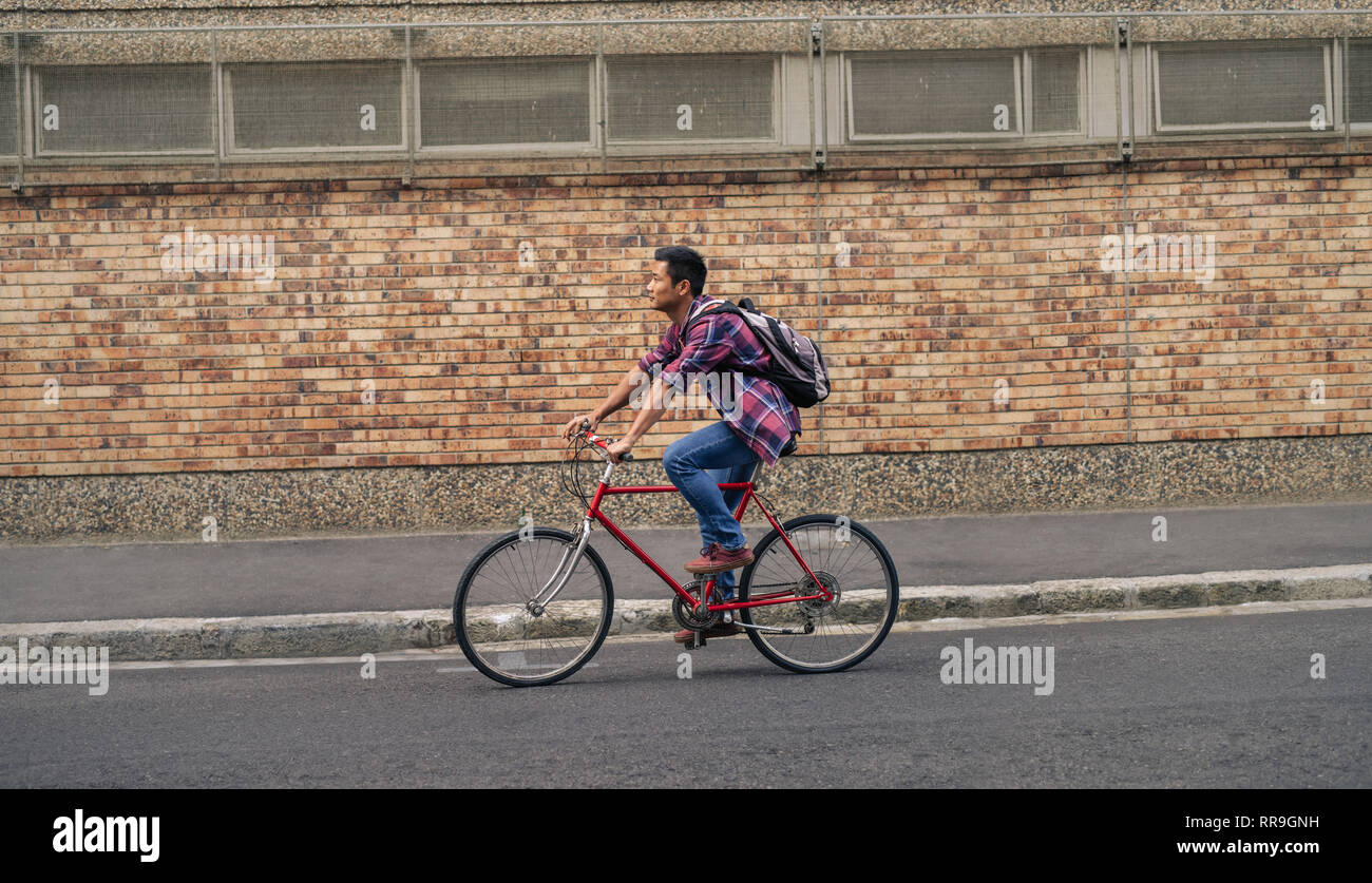 Young Asian man riding his bicycle down a city street Stock Photo