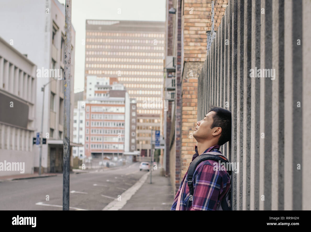 Calm man with eyes closed leaning against a city wall Stock Photo